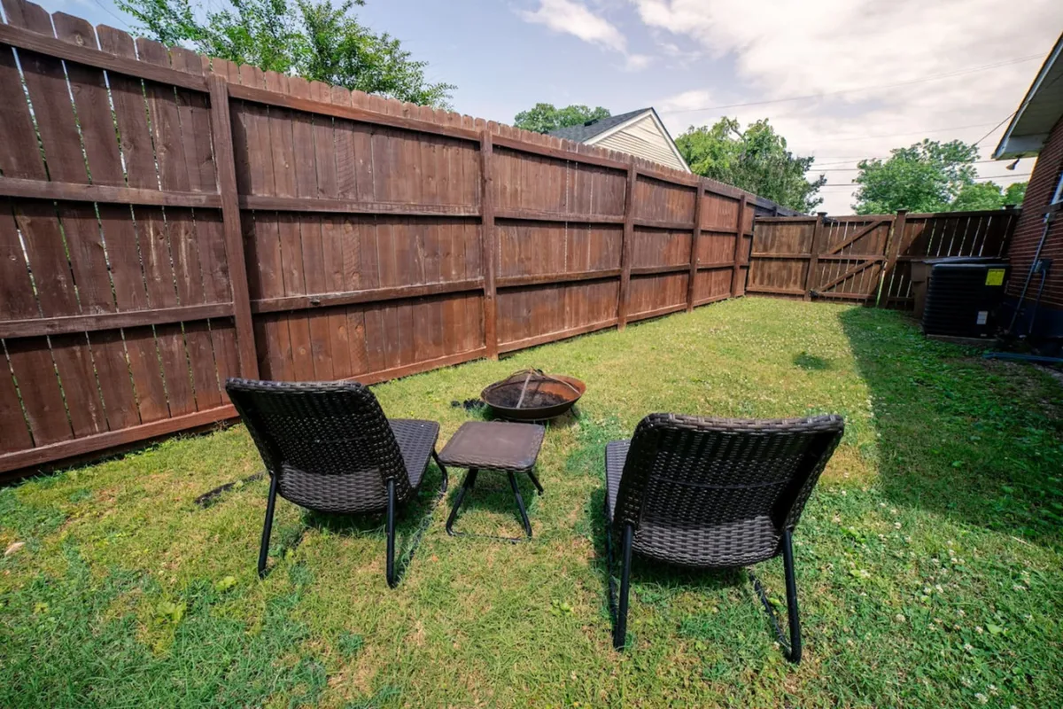 An exterior patio scene featuring two black wicker chairs, a small side table, and a cozy fire pit. The setup invites guests to enjoy both quiet mornings and relaxed evenings outdoors, perfect for unwinding after busy university activities.